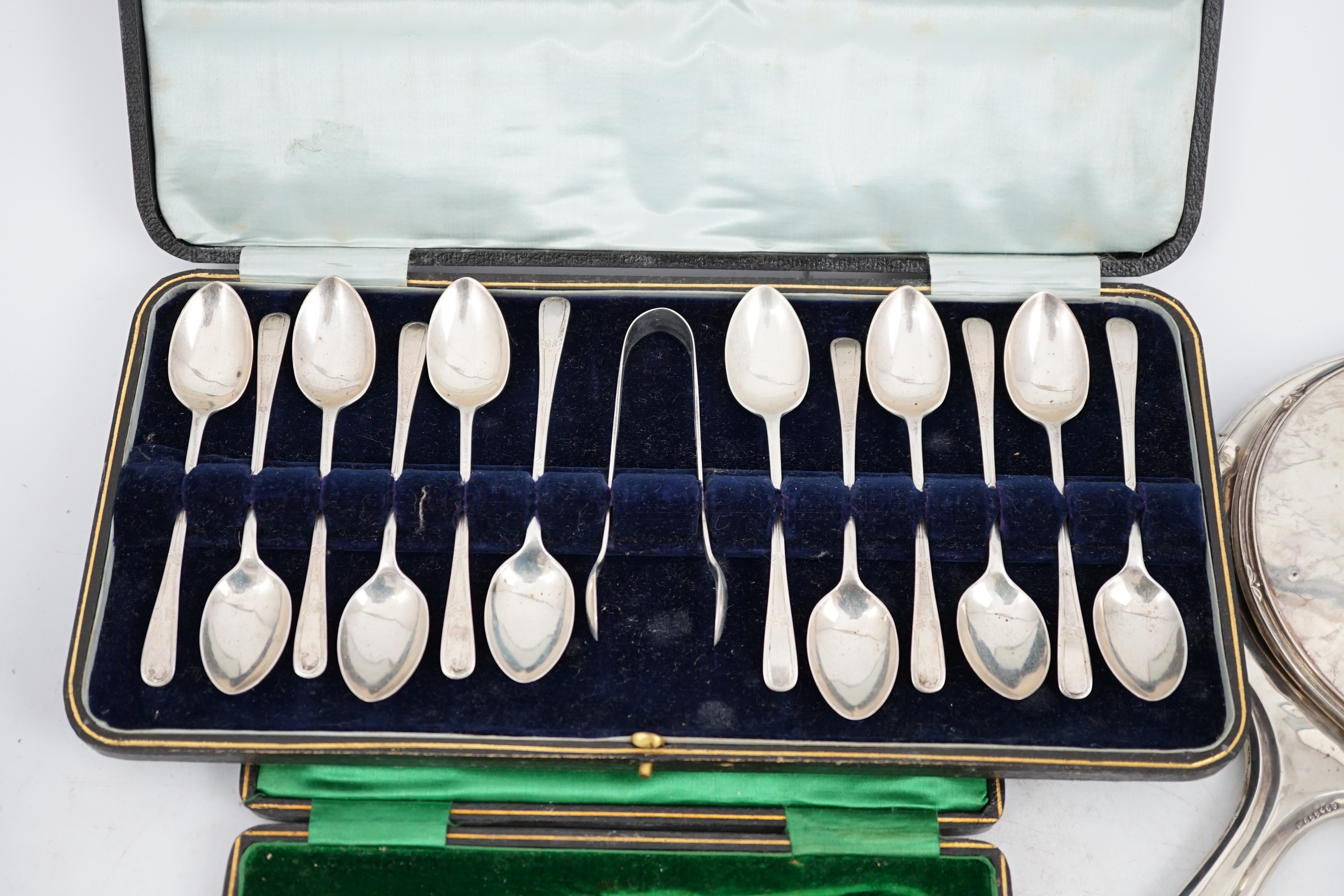 A cased set of twelve George V silver teaspoons with sugar tongs, Sheffield, 1912, two silver hand mirrors, a silver sugar bowl and cream jug, a silver ashtray, a George III silver caddy spoon and cased plated tea knives